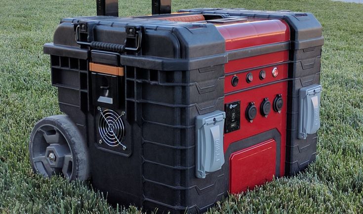 a cooler sitting in the grass with wheels attached to it's sides and an antenna on top