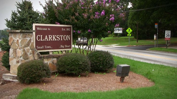 there is a sign that says clarkston in front of some bushes and trees on the side of the road