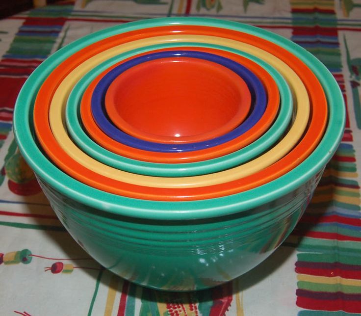 four colorful bowls stacked on top of each other in front of a striped tablecloth