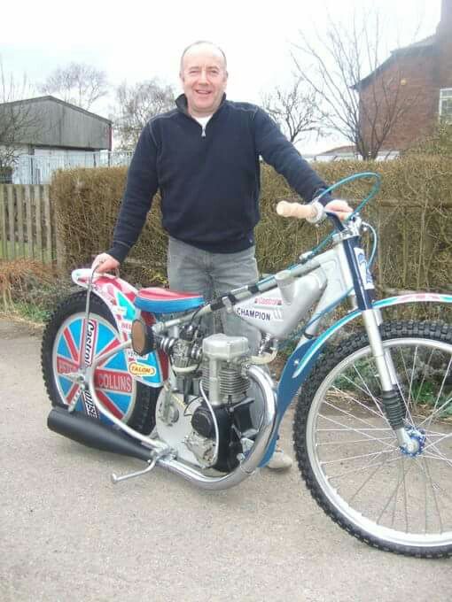 a man is standing next to his bike in the driveway with it's front wheel missing