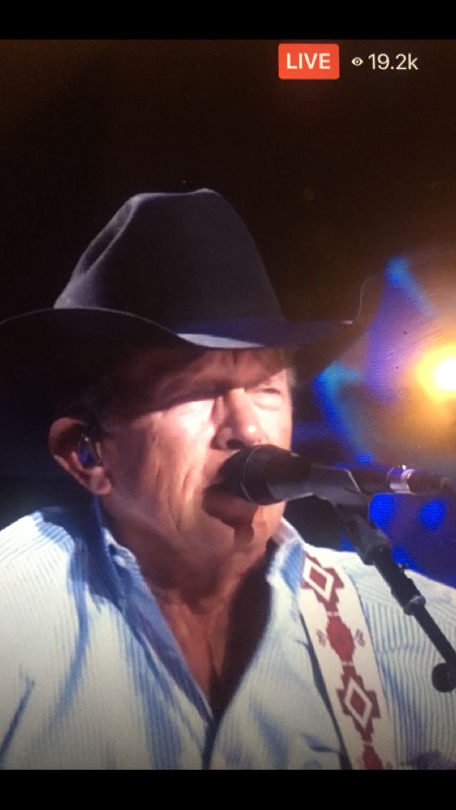 a man wearing a cowboy hat singing into a microphone