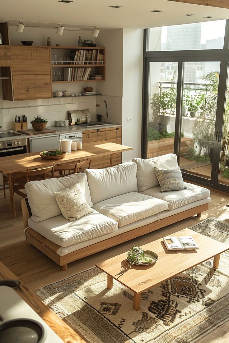 a living room filled with furniture and lots of windows next to a wooden floor covered in plants