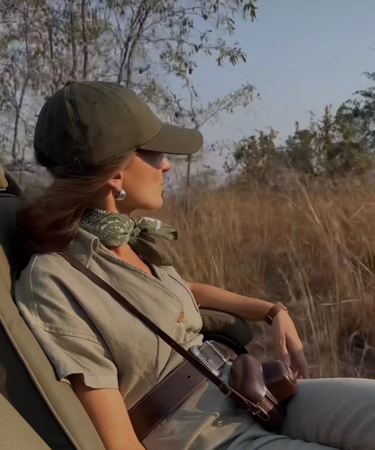 a woman sitting in the back of a safari vehicle with her camera strapped to her shoulder