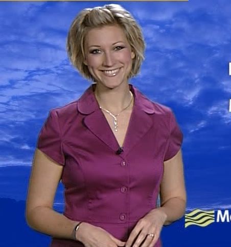 a woman in a purple dress is smiling and holding her hand on her hip while standing against a blue sky with white clouds