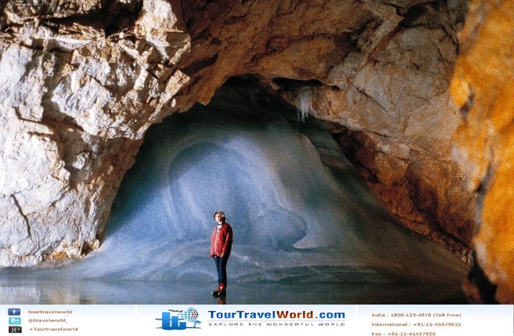 a man standing in the middle of a cave next to a large rock formation with water coming out of it