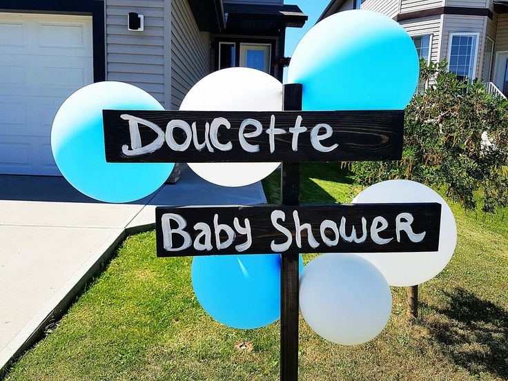 a sign that says doucette baby shower and balloons in front of a house