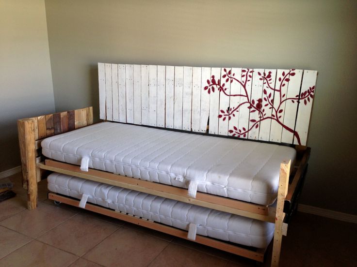 a bed that is made out of pallet wood and has two mattresses attached to it