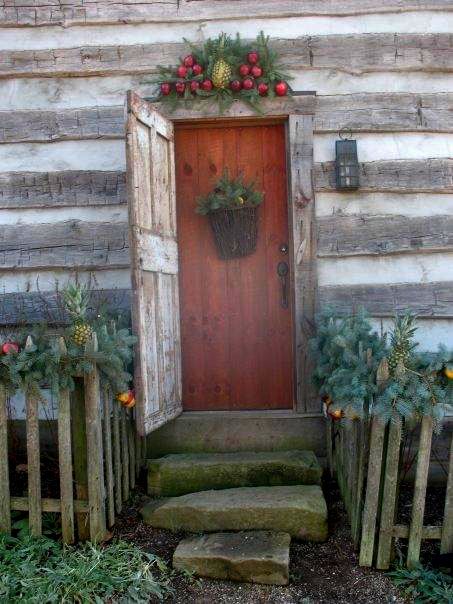 an old door is decorated with fruit and greenery on the front steps, along with stone steps leading up to it