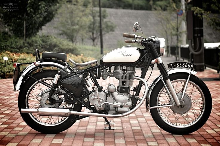 a white and black motorcycle parked on top of a brick road