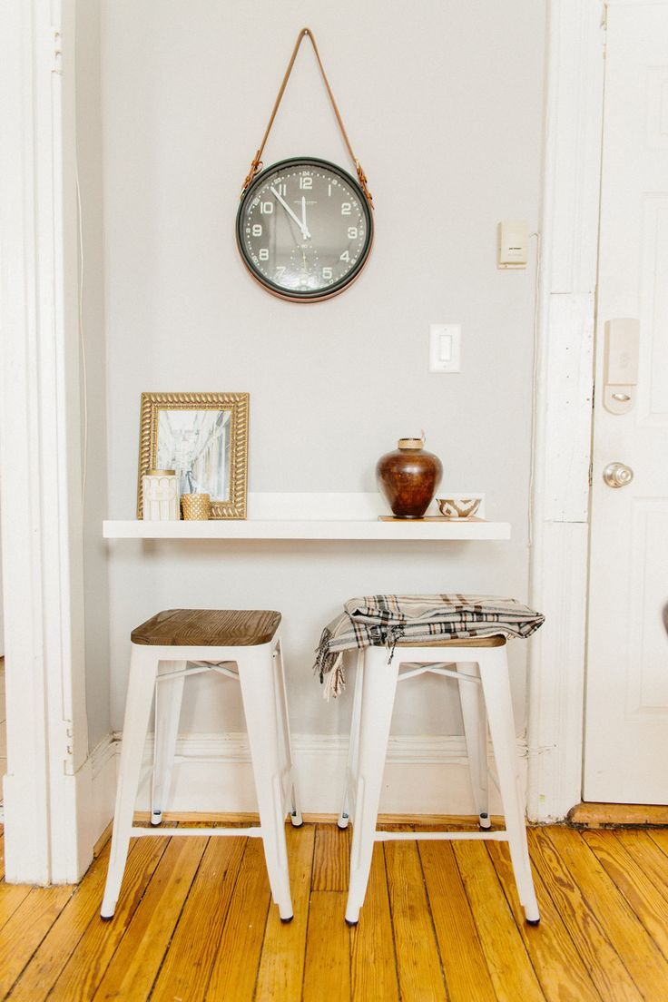 two stools sitting in front of a clock on the wall