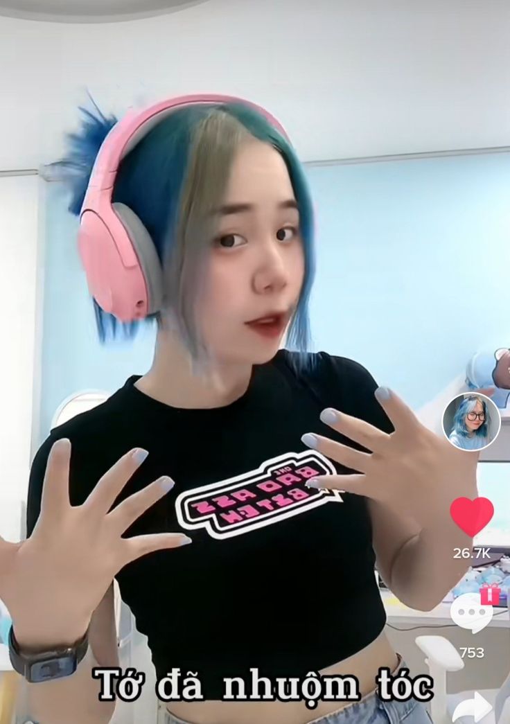 a girl with blue hair wearing headphones and holding her hands out to the side