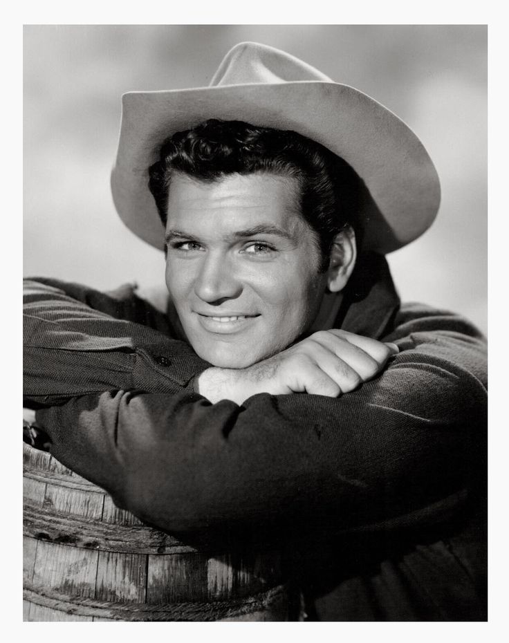 a black and white photo of a man wearing a cowboy hat with his arms crossed