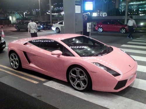 a pink sports car is parked on the street