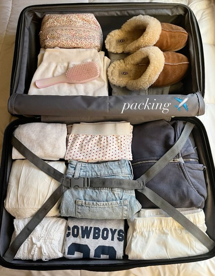 an open suitcase filled with baby clothes and slippers on top of a white bed