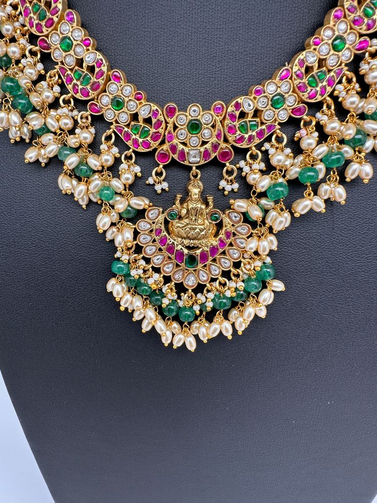 Jadau Kundan Goddess Lakshmi Short Neckline Necklace with Emerald Beads with matching JhumkasColor : GoldenSize : Necklae Length : 14 Inches; No EarringsStones : Jadau Kundan Red Green Clear Jadau Kundan Emerald Beads Emerald Beads Necklace, Necklace For Neckline, Emerald Bead, Goddess Lakshmi, Indian Jewelry, Red Green, Emerald, Beaded Necklace, Beads