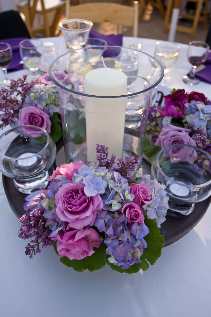 a centerpiece with flowers and candles on a table