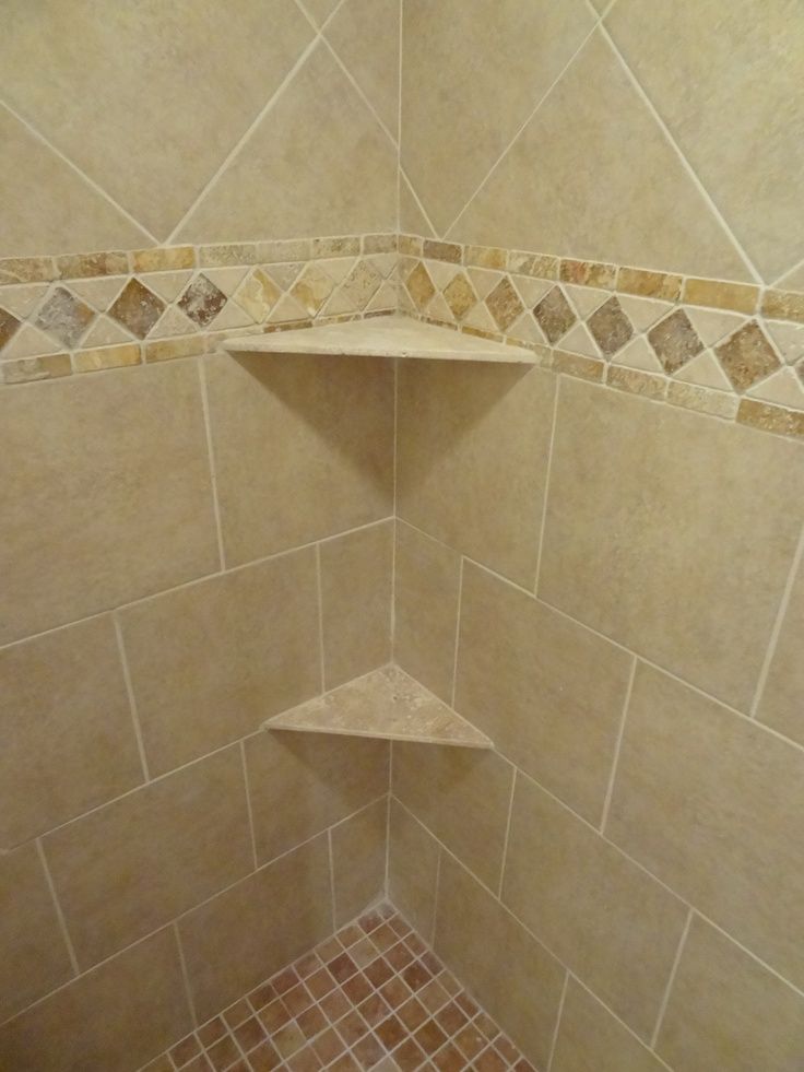 the corner of a shower with tiled walls and floor