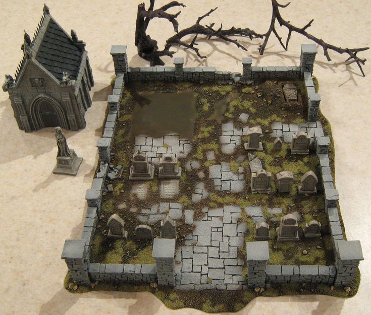 a miniature model of a medieval castle with graves and tombstones on the ground next to a dead tree