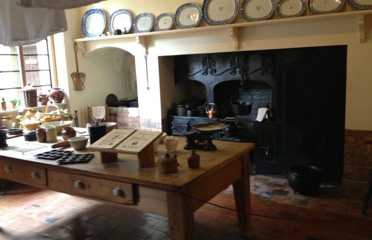 an old fashioned kitchen with many plates on the wall