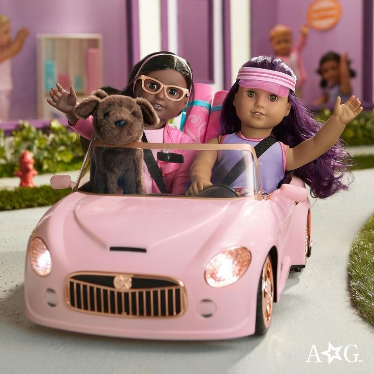 two dolls are riding in a pink toy car with a teddy bear on the front