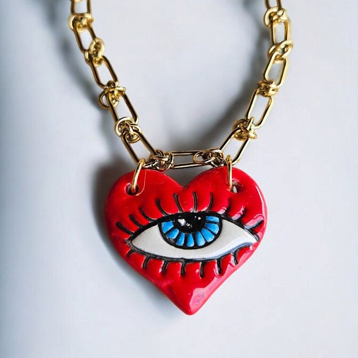 This unique necklace features a vibrant red heart-shaped ceramic pendant with a protective evil eye at its center, symbolizing love and protection. The pendant hangs from a durable stainless steel chain, making it both stylish and long-lasting. Perfect for those who appreciate handmade jewelry with a touch of symbolism, this piece is great for everyday wear or as a thoughtful gift. The combination of the red heart and evil eye brings together love, passion, and good fortune in a single beautiful accessory. Material : Stainless Stain Chain, Ceramic Evil Eye Length : 45 centimeters / 17.72 inches Chain Ceramic, Ceramic Evil Eye, Heart Ceramic, Necklace Evil Eye, Protection Jewelry, Chain Making, Stainless Steel Chain Necklace, Christmas Necklace, Ceramic Necklace