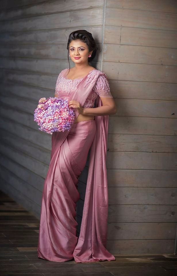 a woman in a pink sari holding a bouquet of flowers and posing for the camera