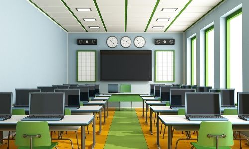 a classroom with rows of desks and computer monitors on each side of the room