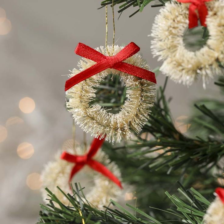 an ornament hanging from a christmas tree decorated with red and white ribbon bows