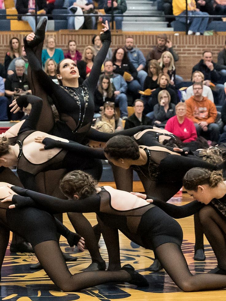 a group of women in black and white leotards doing tricks on a basketball court