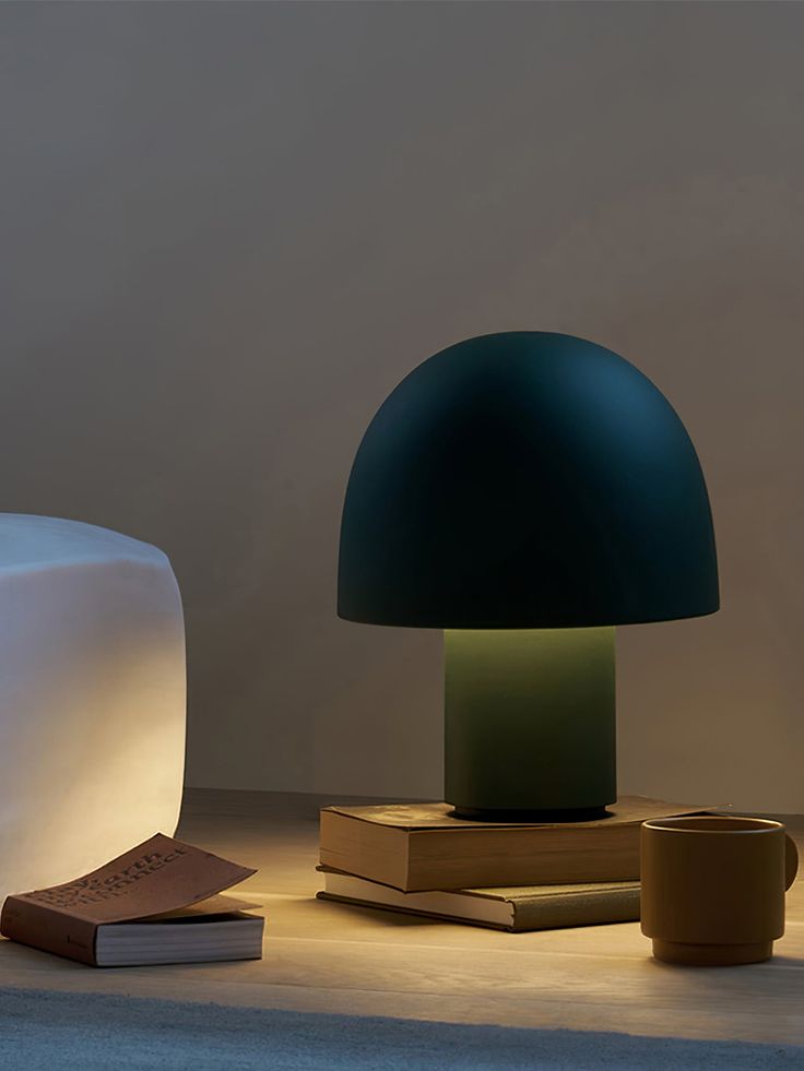 a table lamp sitting on top of a wooden table next to a book and cup