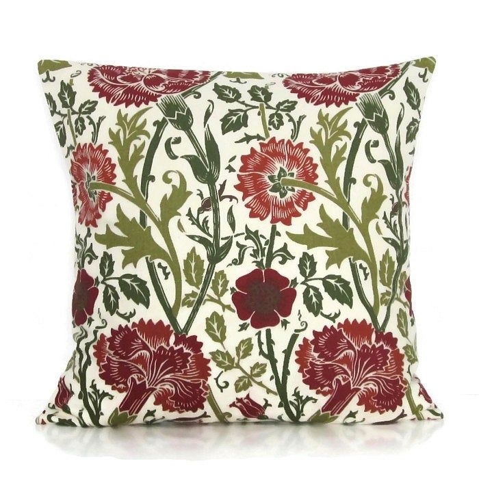 a red and green floral pillow on a white background, with leaves and flowers all over it