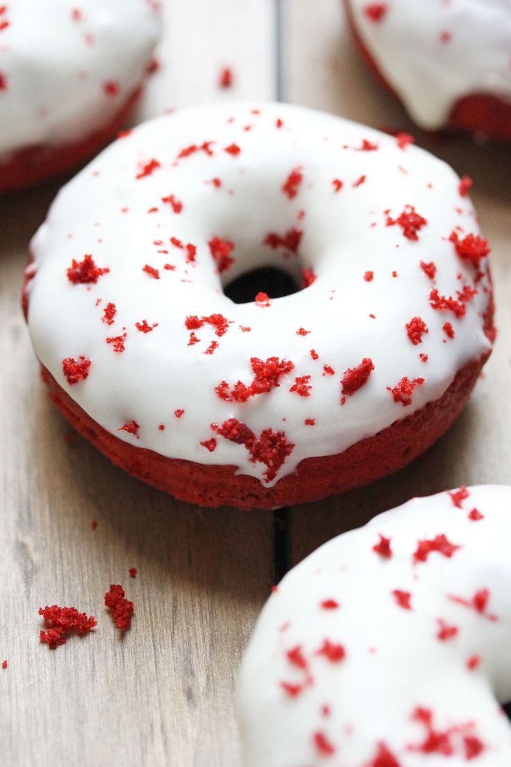 red and white sprinkled donuts sitting on top of a wooden table