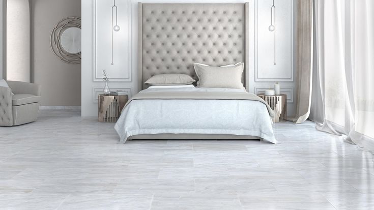 a bedroom with white walls and flooring has a beige upholstered headboard