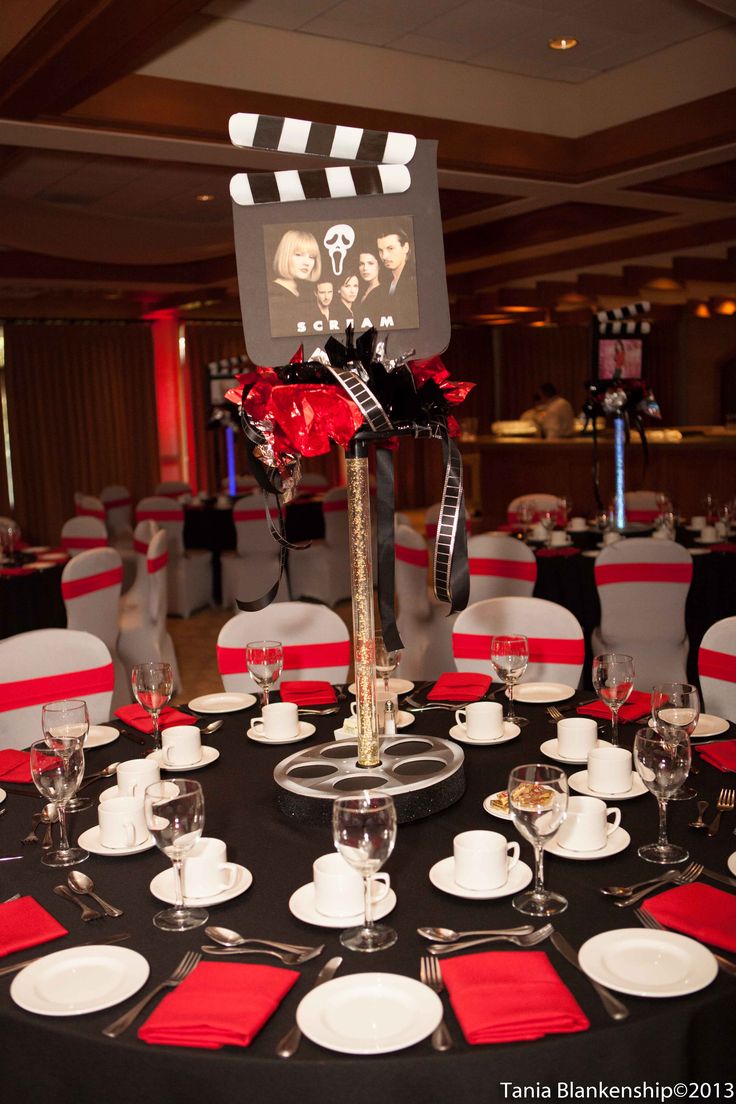 a black table topped with white plates and red napkins next to a movie screen