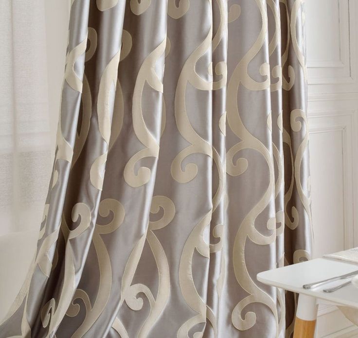 a white table and chair in front of a curtain with an intricate design on it