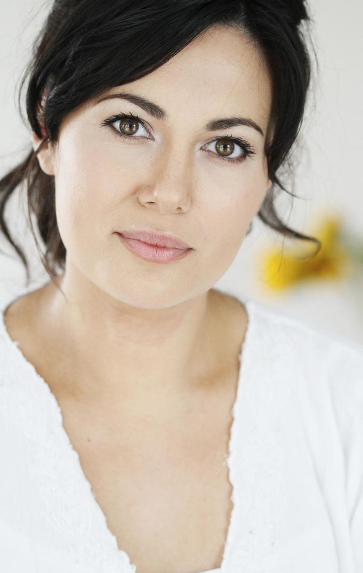 a close up of a person wearing a white shirt and flowers in the back ground