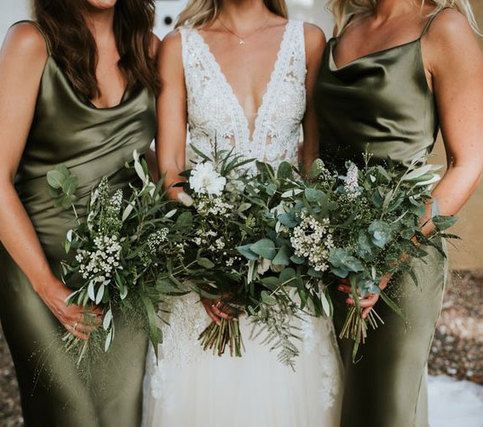 three bridesmaids in green dresses holding bouquets