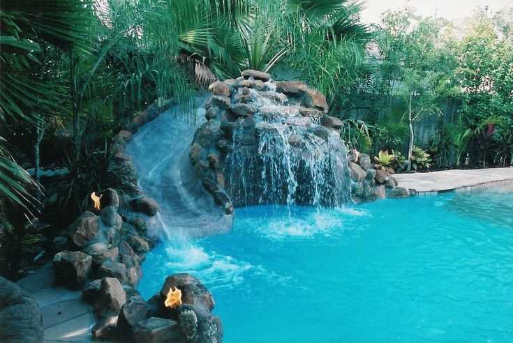 an outdoor pool with waterfall and rocks