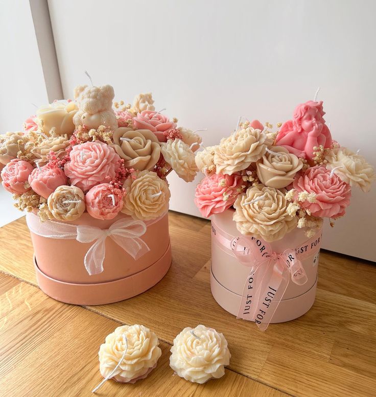 two pink and white flowers are sitting in small boxes on the floor next to each other