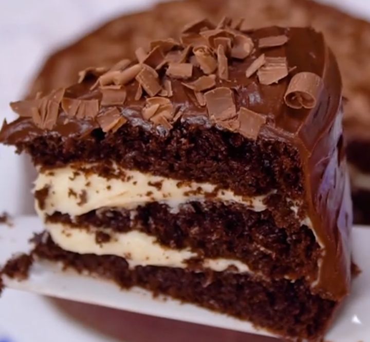 a piece of chocolate cake with white frosting and chocolate shavings on top