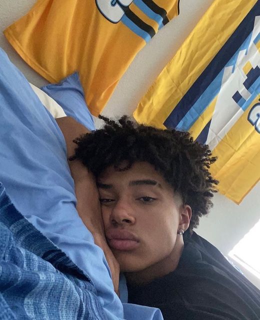 a young man laying in bed with his head on the pillow