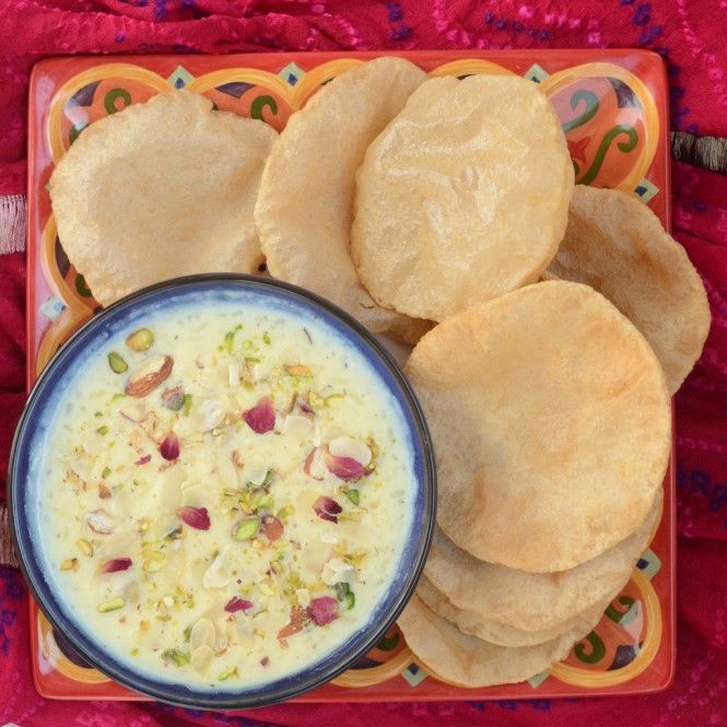 a plate with some pita bread and a bowl of dip next to it on a colorful table cloth