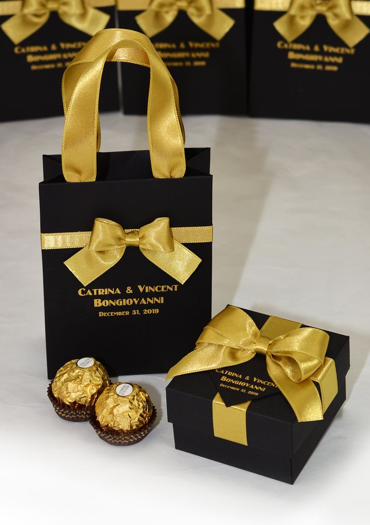 two black boxes with gold ribbon and chocolates