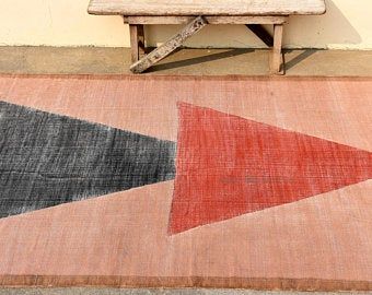 a wooden bench sitting next to a rug on top of a floor with an arrow design