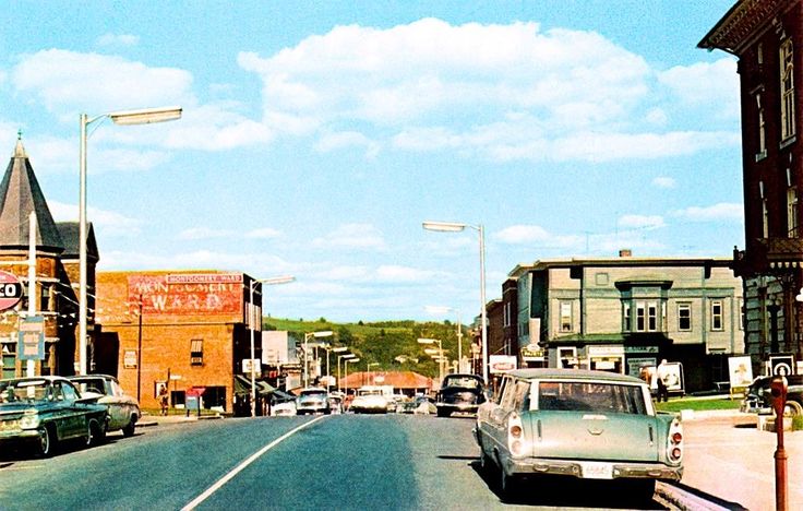 an old photo of cars driving down the street