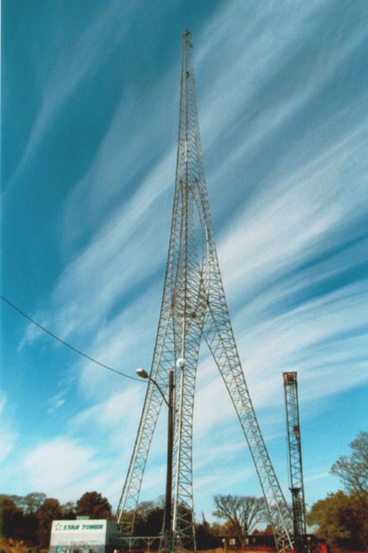 a tall metal tower sitting on top of a lush green field under a blue sky