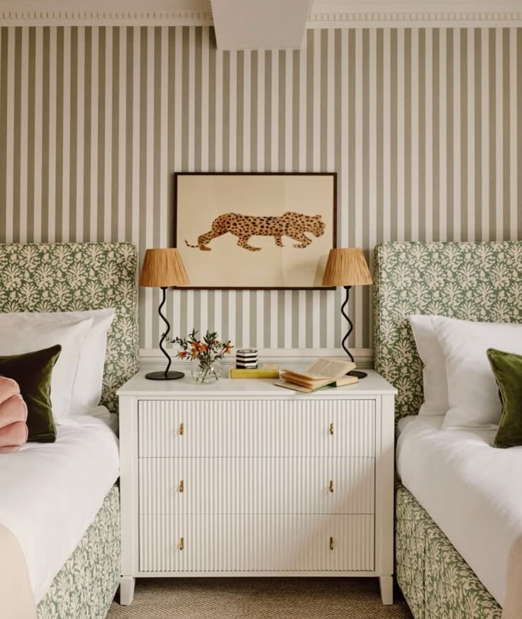 two beds in a bedroom with green and white wallpaper, one has a cheetah print on the wall