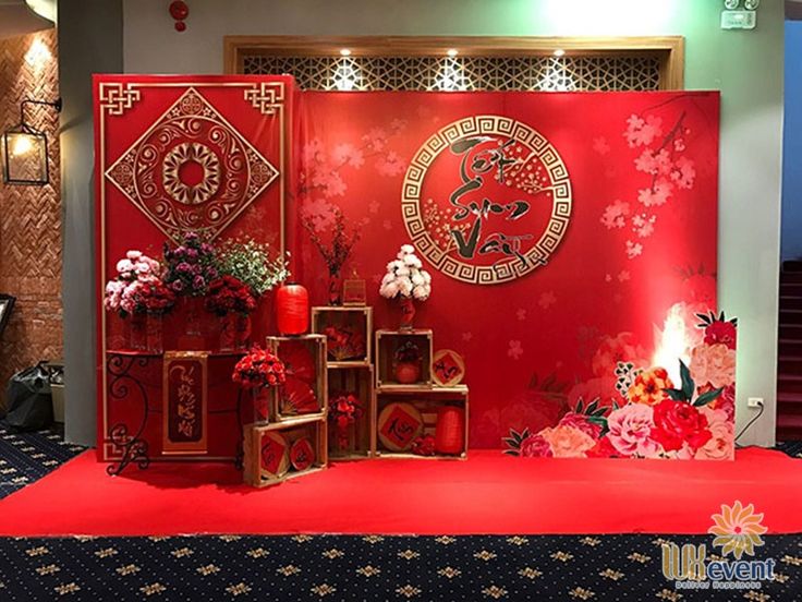 a red stage with flowers and decorations on the floor, in front of a wall