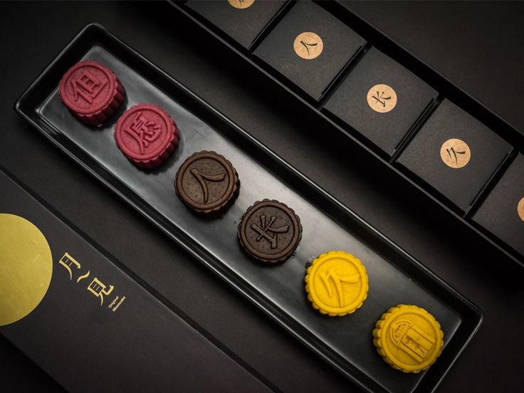 some cookies are sitting on top of a black tray with yellow and red frosting