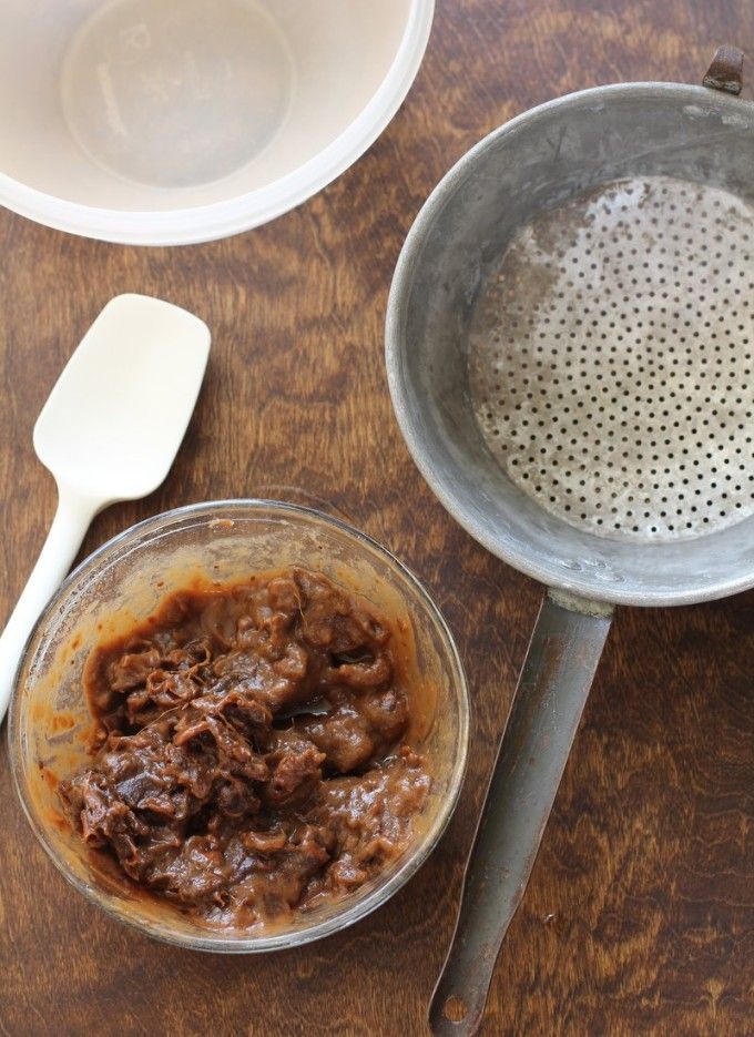 a wooden table topped with two metal pans filled with food next to spoons